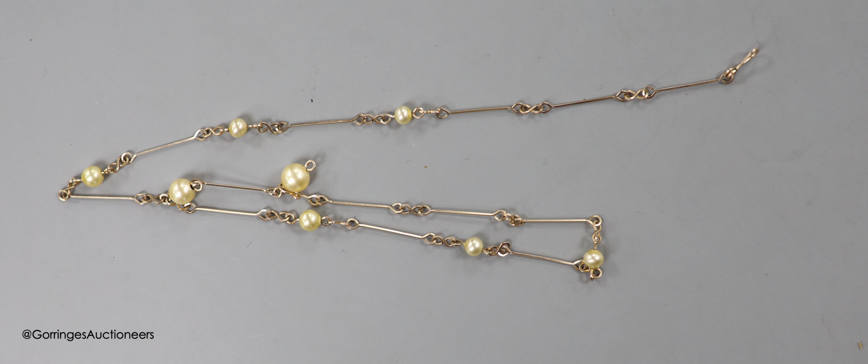 An early 20th century yellow metal and three stone diamond set bar brooch, 36mm, gross 1.6 grams and a yellow metal and simulated pearl set neck chain, 47cm, gross3.8 grams.